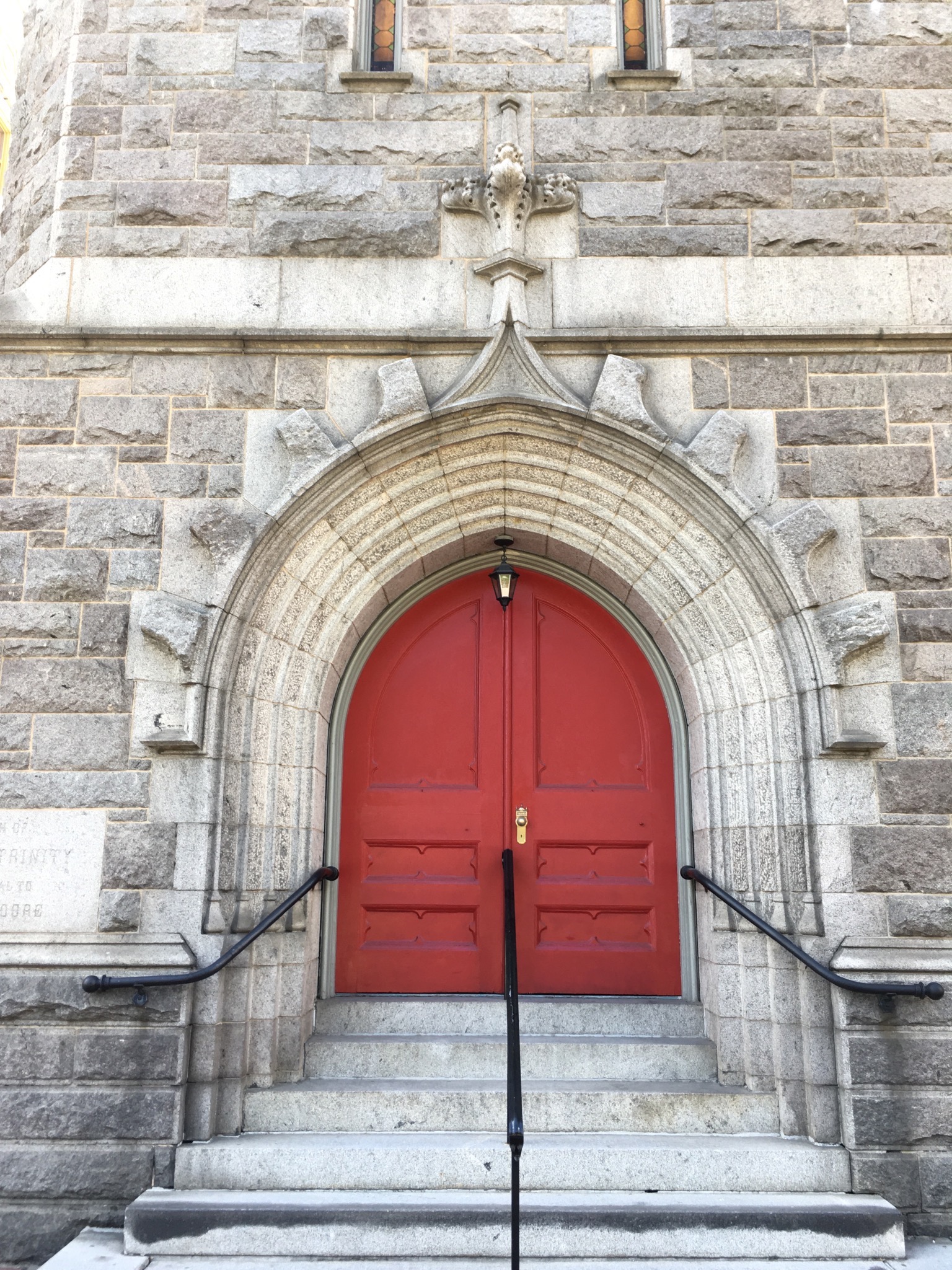 a red door at the top of the steps of a stone church