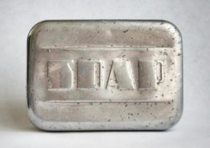 Close up photograph of a metal soap container on a white background